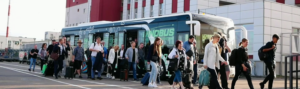 Passenger electric bus at airport with passengers walking out